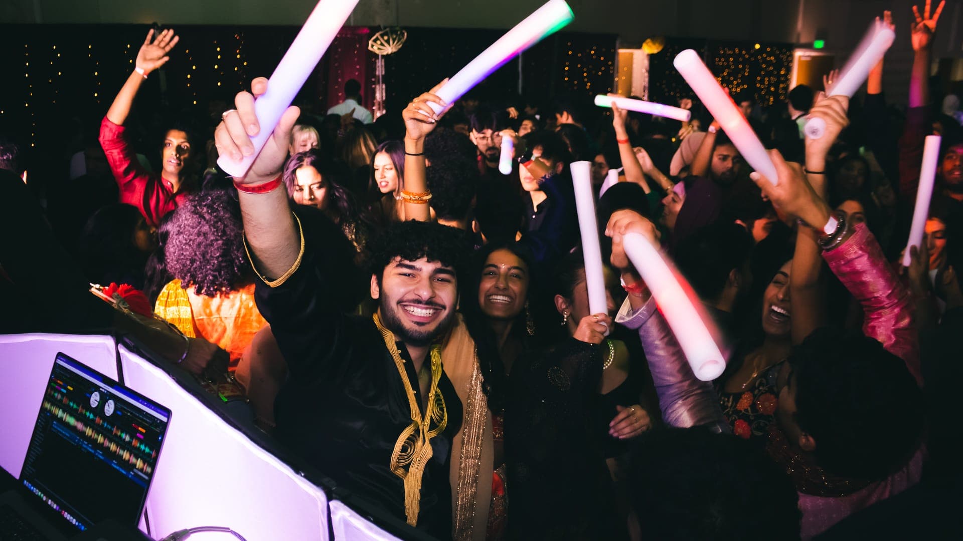 A packed student crowd dancing with illuminated foam sticks