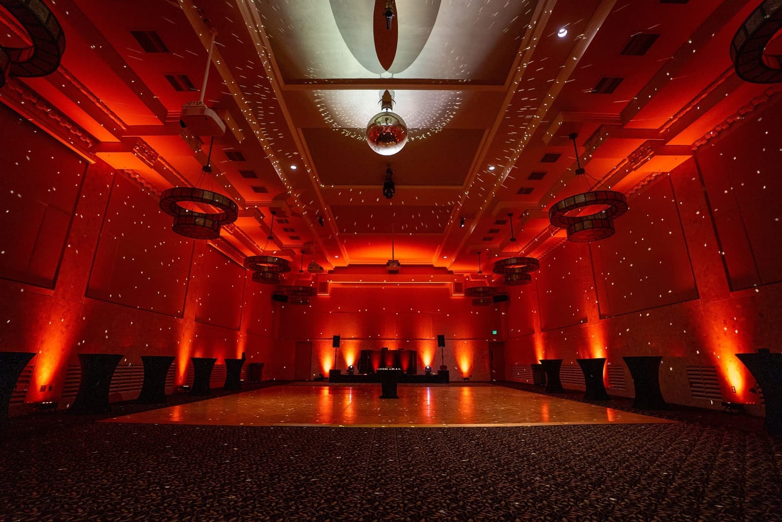 A formal venue transformed with red uplighting and disco reflections