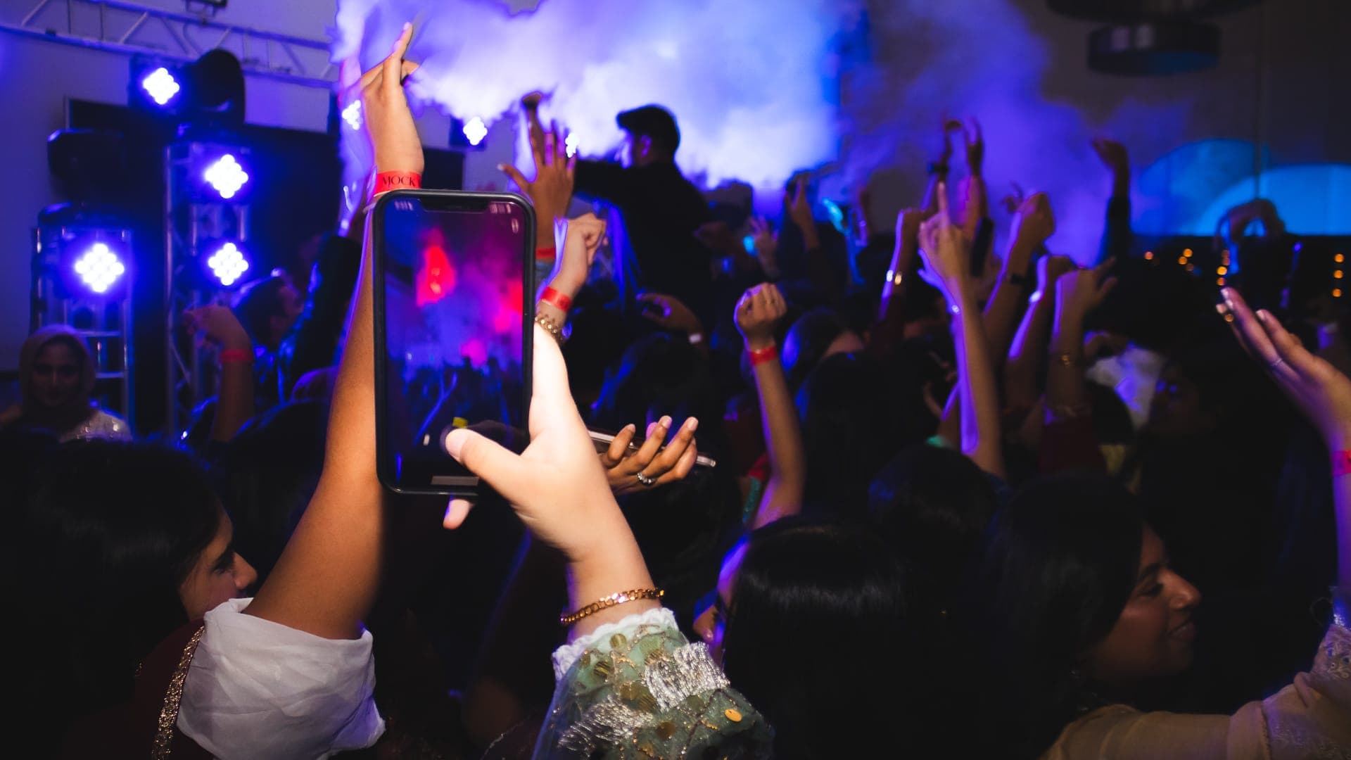 Students raising their hands beneath blue lights and atmospheric effects