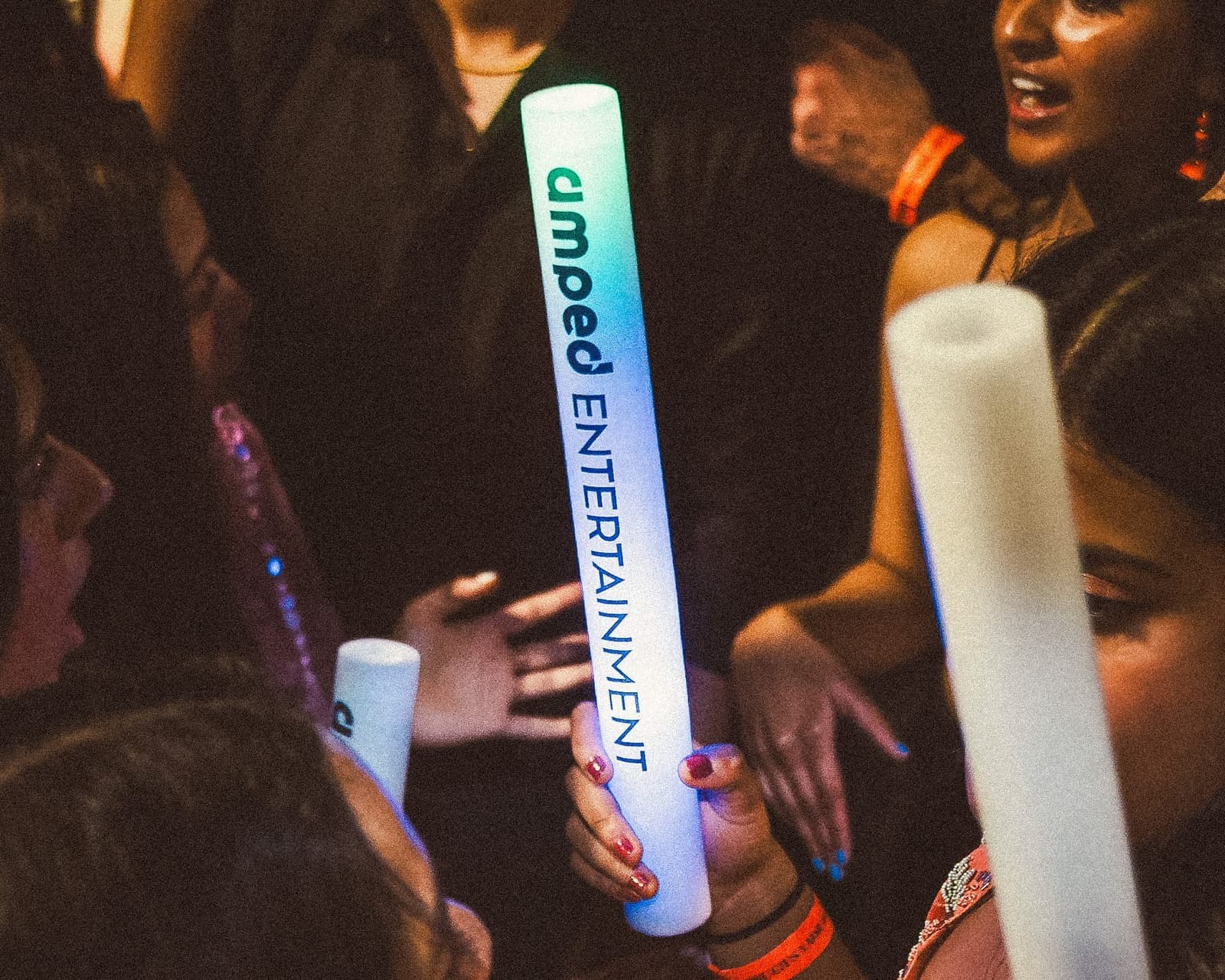 Students celebrating with glowing Amped Entertainment foam sticks at a campus event