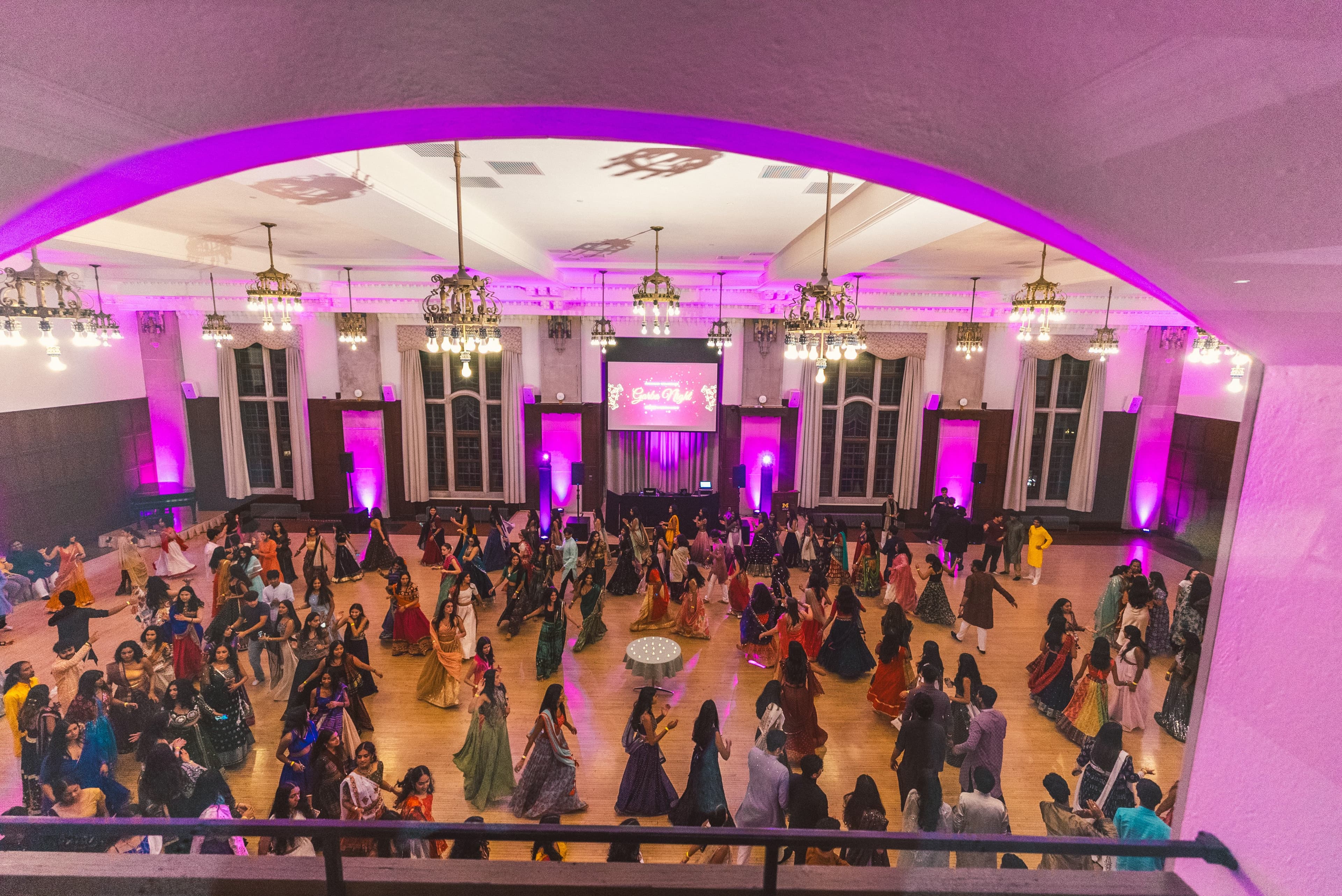 An aerial view of the ballroom full of dancers under pink lighting
