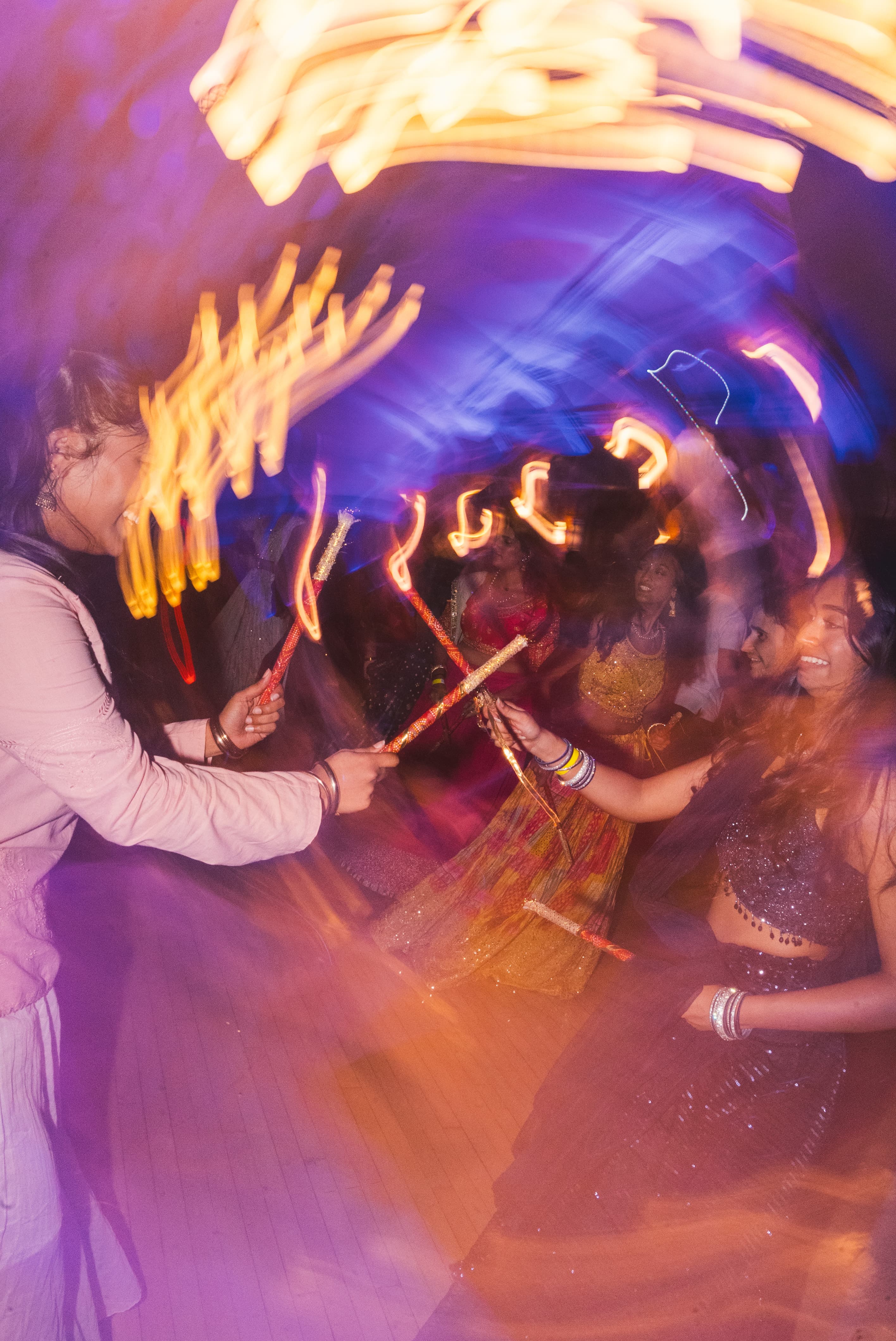Long-exposure light trails from spinning dandiya sticks on the dance floor