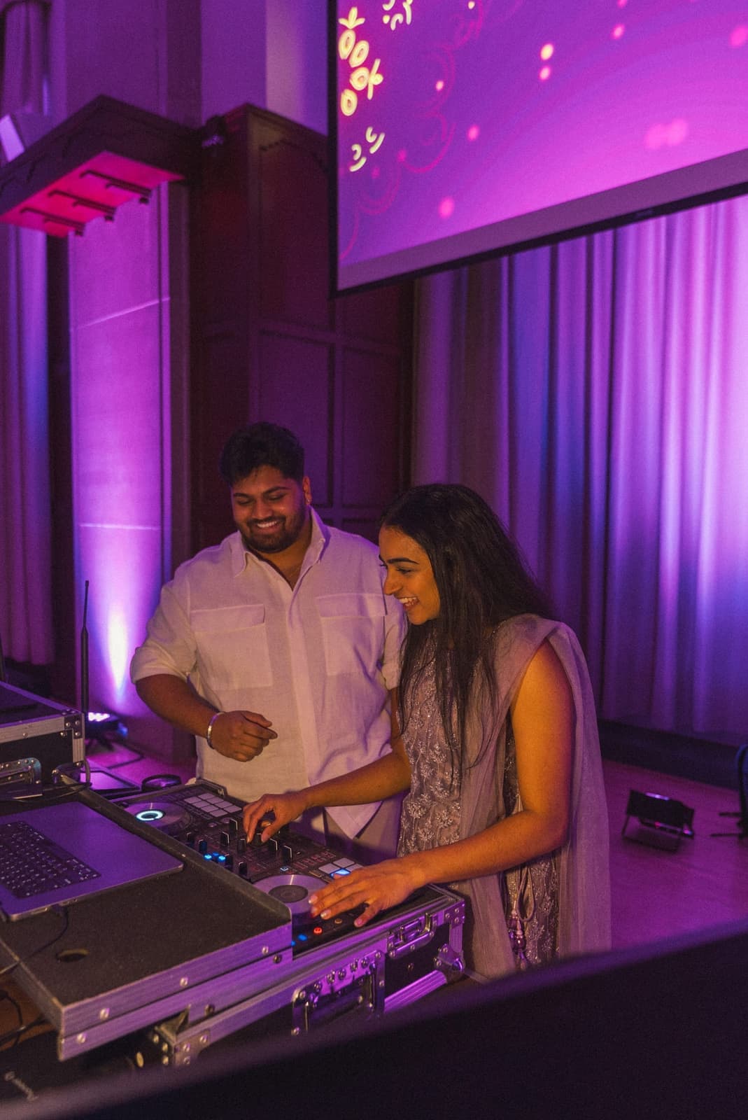 Two Amped crew members working the DJ booth together at a campus show