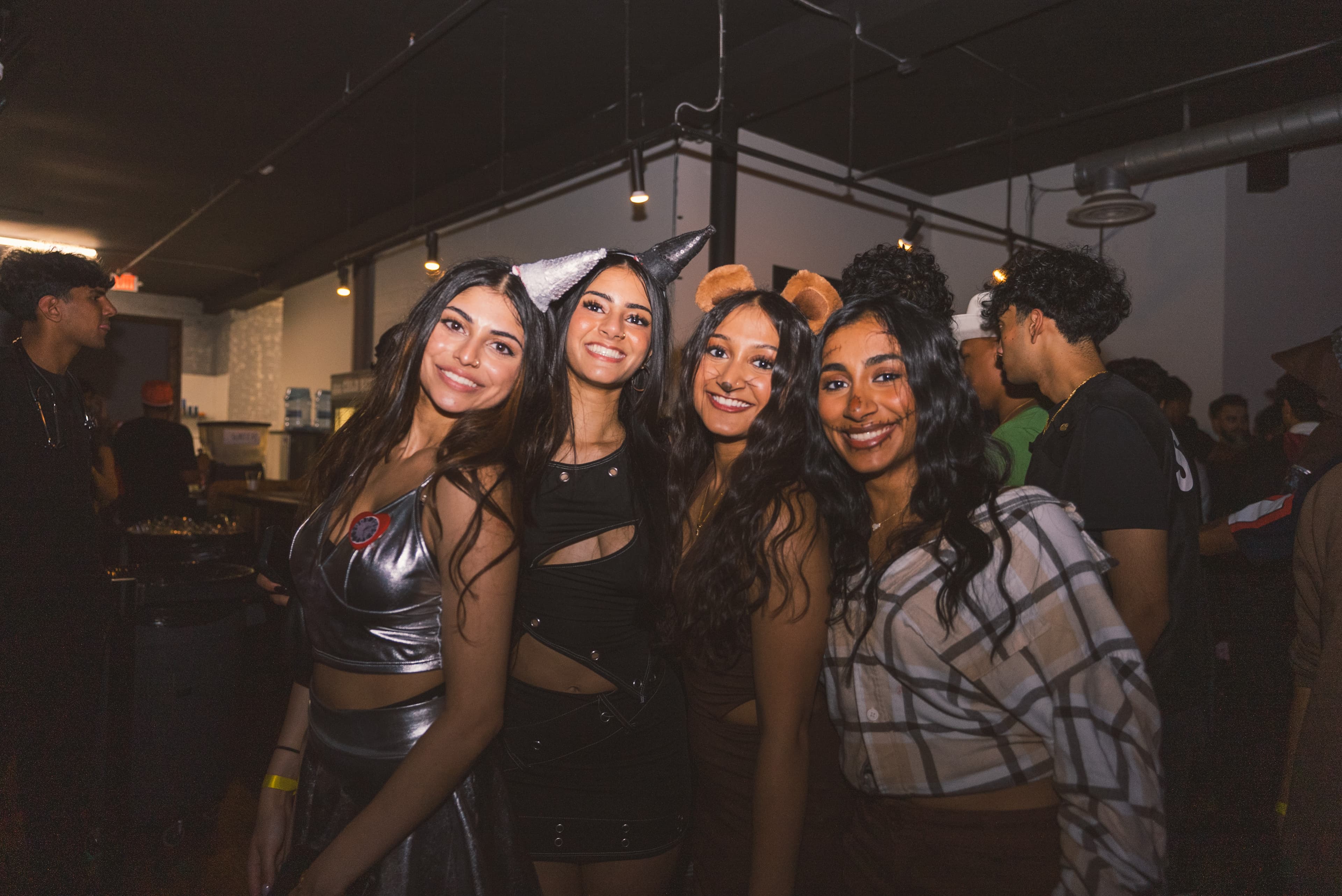 Four friends in dark costumes with horns and bear ears